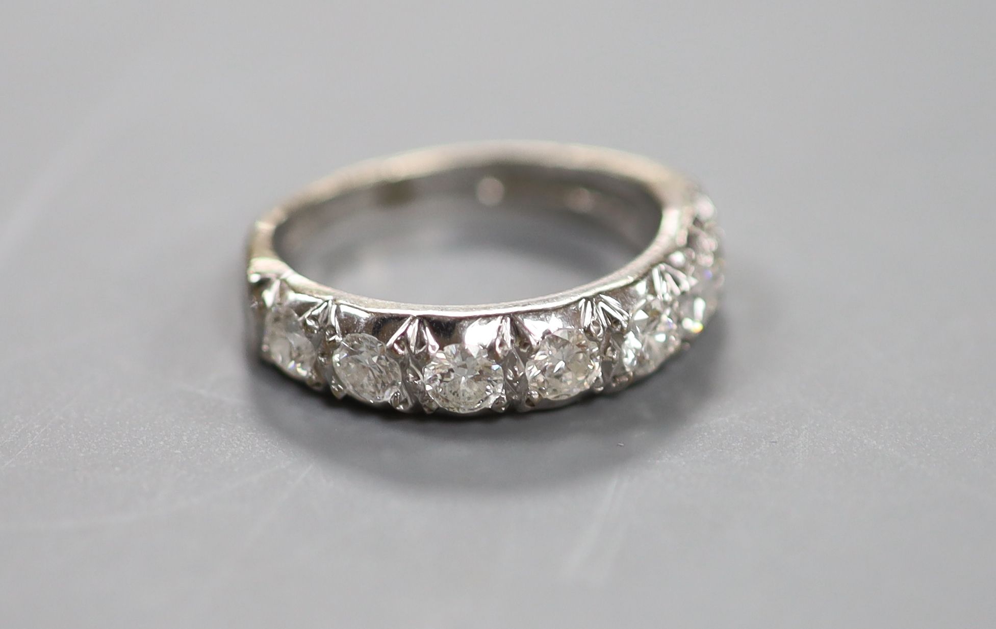 A modern 18ct white gold and seven stone diamond set half hoop ring